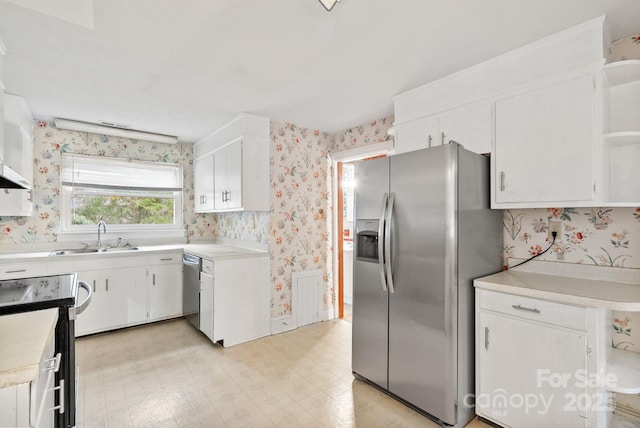 kitchen with wallpapered walls, light floors, light countertops, appliances with stainless steel finishes, and a sink