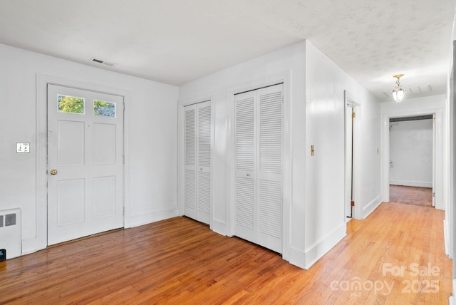 interior space featuring radiator, baseboards, visible vents, and light wood-type flooring