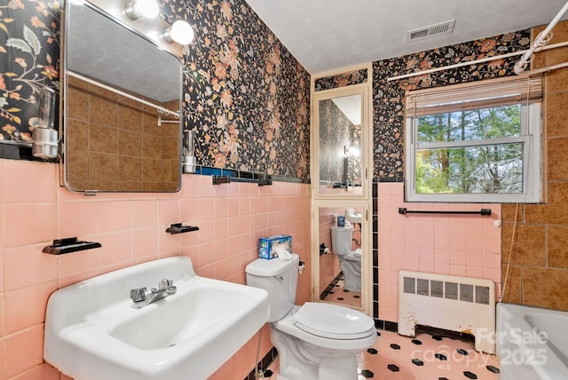 full bath with visible vents, toilet, a sink, radiator heating unit, and a bathtub