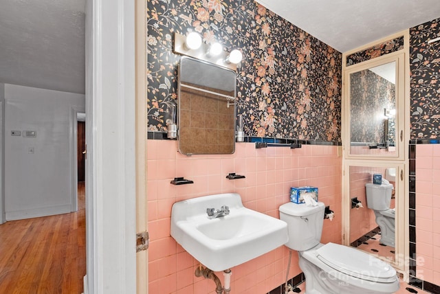 bathroom featuring a wainscoted wall, toilet, wood finished floors, and wallpapered walls