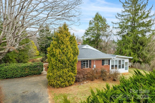 view of side of property with brick siding and a shingled roof