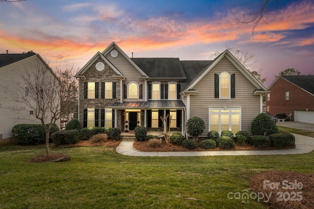 traditional-style home with stone siding, a porch, and a yard