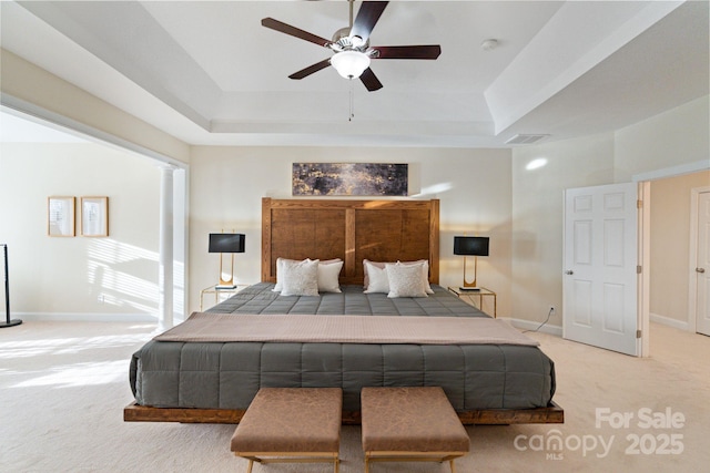 carpeted bedroom featuring a raised ceiling, visible vents, and baseboards