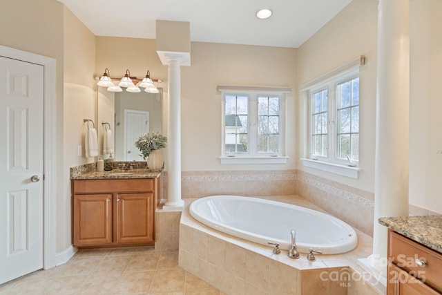 full bath featuring tile patterned flooring, a garden tub, decorative columns, and vanity