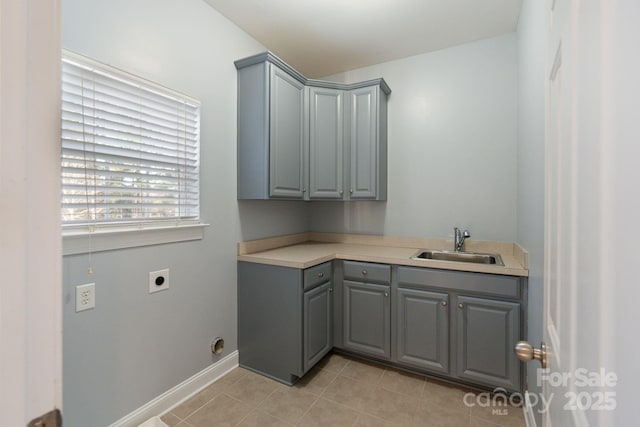 washroom featuring light tile patterned floors, hookup for an electric dryer, a sink, baseboards, and cabinet space