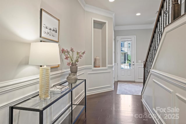 entryway with a wainscoted wall, stairs, dark wood-type flooring, and ornamental molding