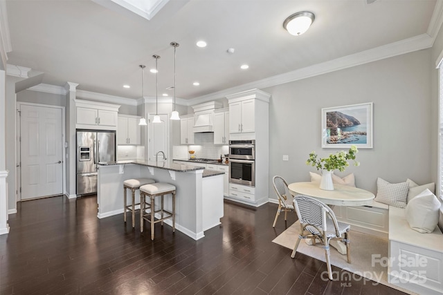 kitchen with a breakfast bar area, appliances with stainless steel finishes, breakfast area, and white cabinetry