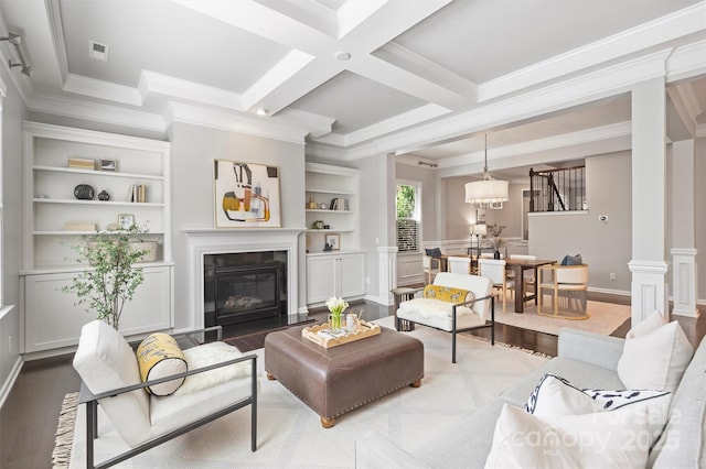 living area with crown molding, a fireplace with flush hearth, beamed ceiling, decorative columns, and wood finished floors