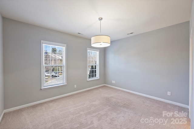 spare room with baseboards, visible vents, and light carpet