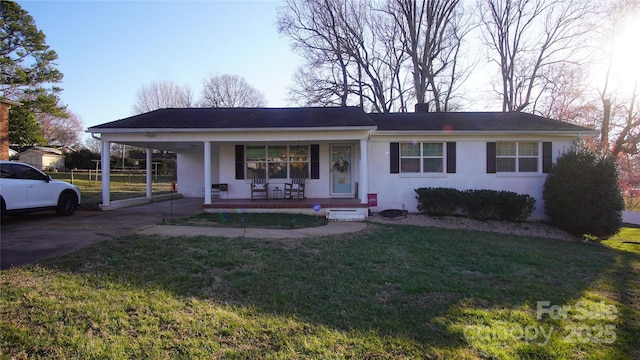 view of front of home with brick siding, a chimney, a porch, a carport, and a front lawn