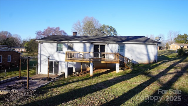 back of house featuring a wooden deck, central AC unit, a chimney, a yard, and brick siding