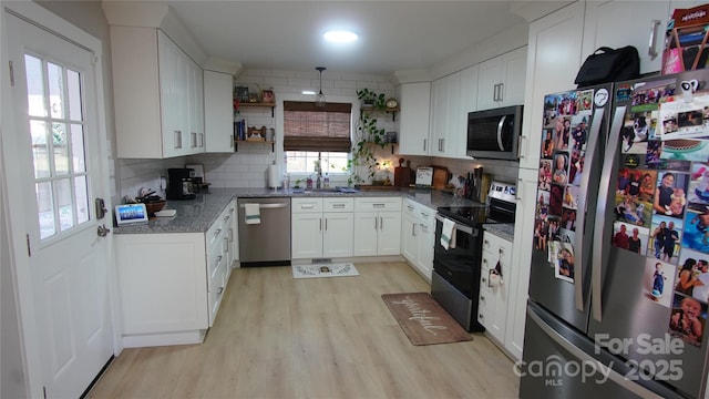 kitchen featuring light wood finished floors, decorative backsplash, appliances with stainless steel finishes, white cabinetry, and open shelves