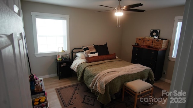 bedroom with a ceiling fan, light wood-style flooring, and baseboards