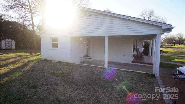 view of side of property with a yard, a storage unit, an outbuilding, and brick siding