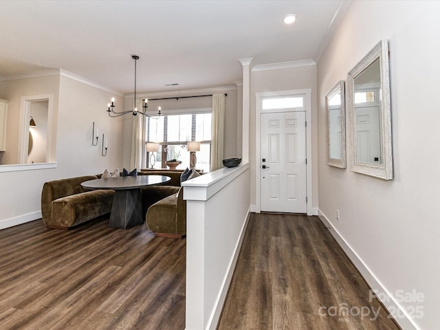 foyer entrance featuring dark wood-style floors, baseboards, an inviting chandelier, and crown molding