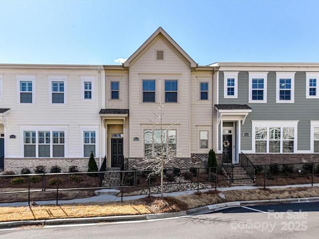 multi unit property featuring brick siding and a fenced front yard