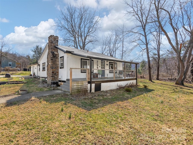 view of front facade with a chimney, a front lawn, and a porch