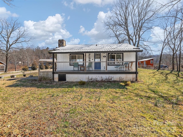 view of front of home featuring a chimney, a porch, a standing seam roof, metal roof, and a front lawn