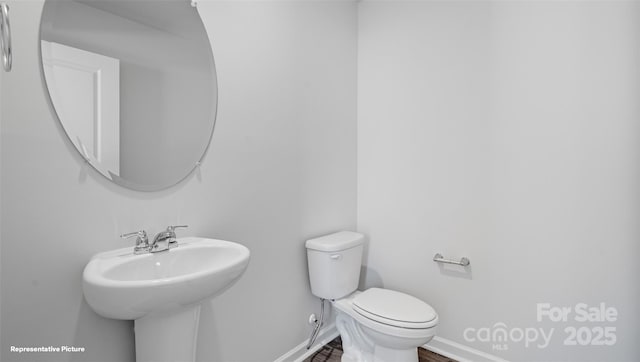 bathroom featuring toilet, baseboards, and a sink