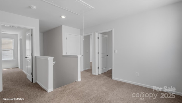 empty room with carpet floors, attic access, and baseboards