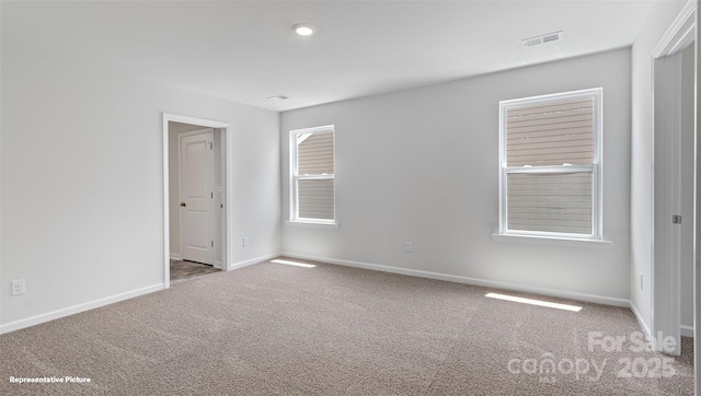 carpeted empty room featuring a healthy amount of sunlight, visible vents, and baseboards