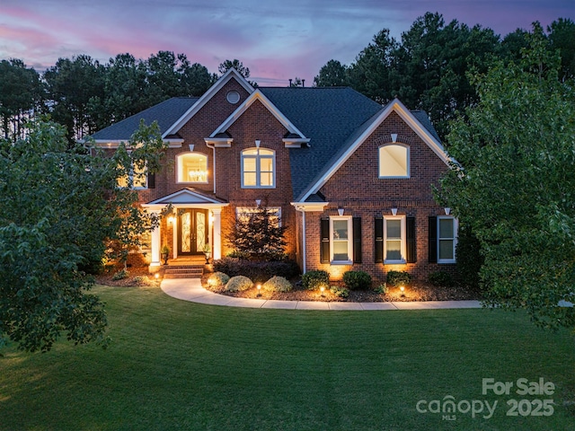 traditional-style home with a yard, brick siding, and french doors