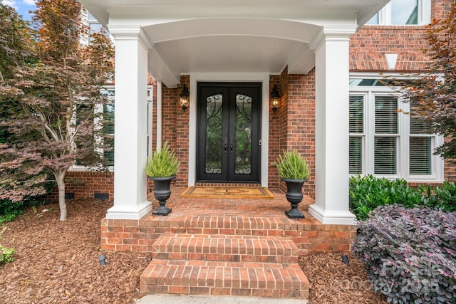 entrance to property featuring french doors and brick siding