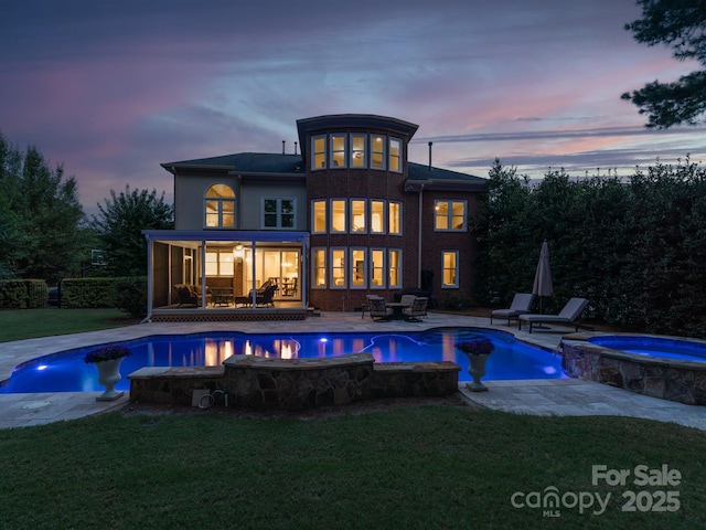 back of house featuring a pool with connected hot tub, a yard, and a patio