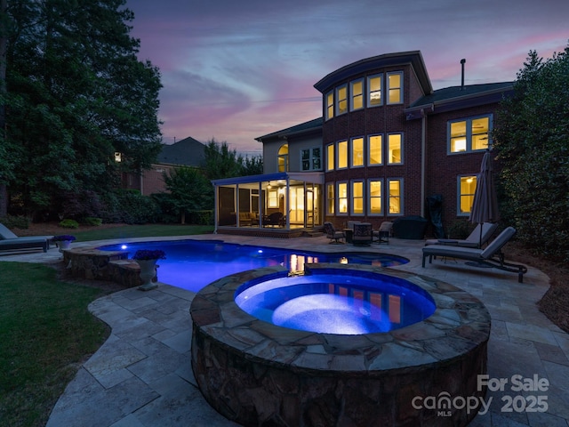 outdoor pool with a sunroom, a patio, and an in ground hot tub