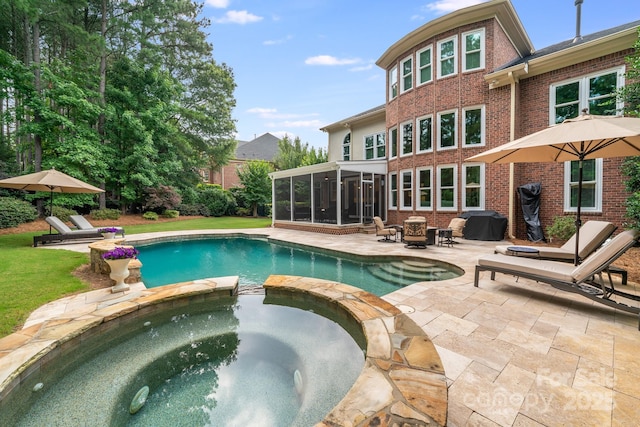 view of pool featuring a pool with connected hot tub, a sunroom, a patio, and area for grilling