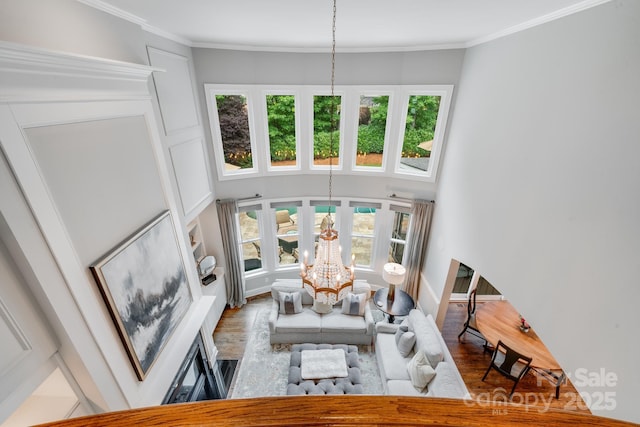 living area featuring ornamental molding, plenty of natural light, wood finished floors, and an inviting chandelier