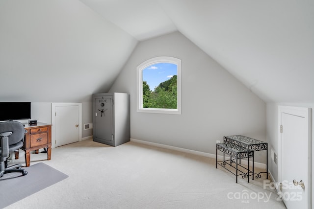 office area featuring light carpet, vaulted ceiling, and baseboards