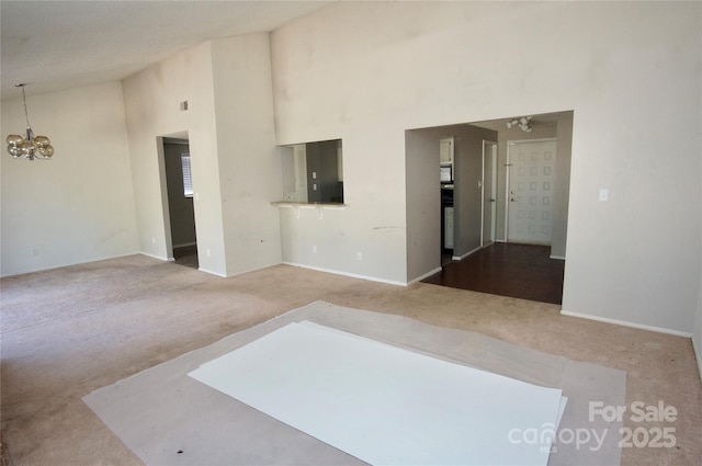 carpeted spare room with high vaulted ceiling and a notable chandelier