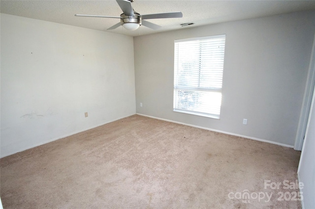 empty room with carpet floors, visible vents, ceiling fan, and a textured ceiling