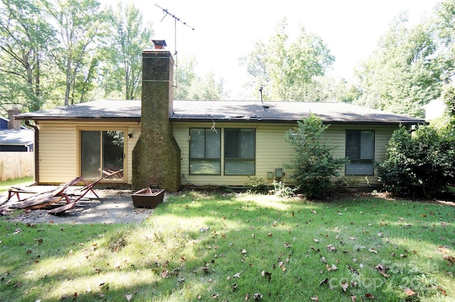 back of house with a chimney, a fire pit, a lawn, and a patio