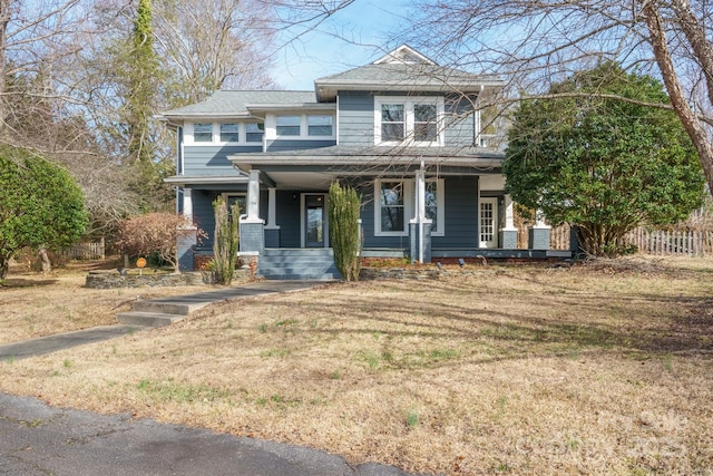 view of front of house with a porch, a front lawn, and fence