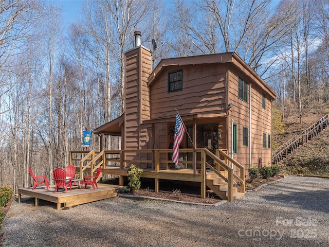 exterior space with a chimney, stairway, and a wooden deck