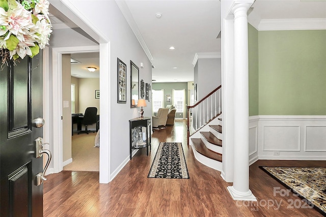 entryway with decorative columns, ornamental molding, wood finished floors, and wainscoting