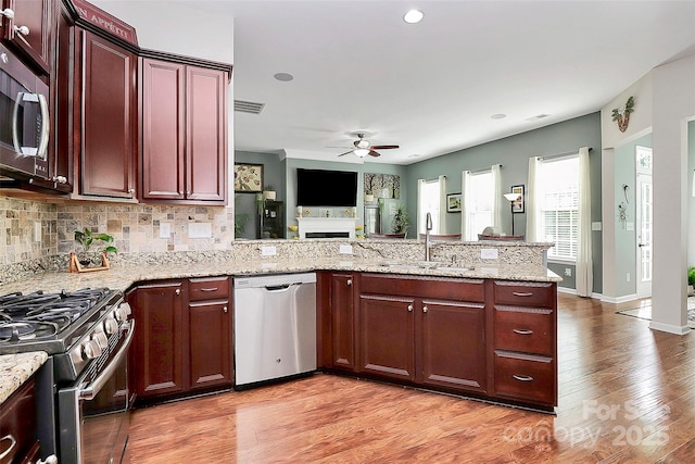 kitchen with stainless steel appliances, a peninsula, a sink, visible vents, and a ceiling fan