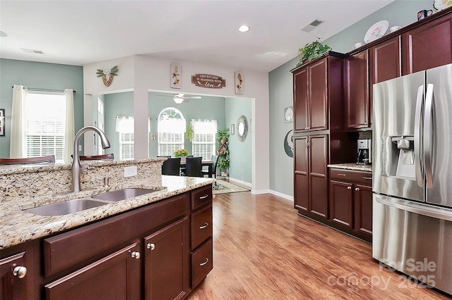 kitchen with a sink, stainless steel fridge, visible vents, and light wood-style floors