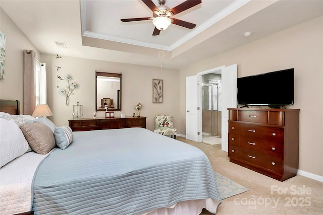 bedroom with a tray ceiling, crown molding, light colored carpet, connected bathroom, and baseboards