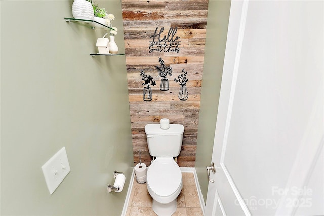 bathroom with baseboards, tile patterned floors, toilet, and wooden walls