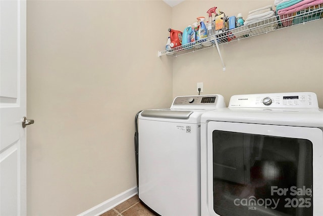 laundry area with laundry area, tile patterned floors, washing machine and clothes dryer, and baseboards