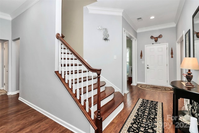 foyer featuring baseboards, visible vents, wood finished floors, and ornamental molding