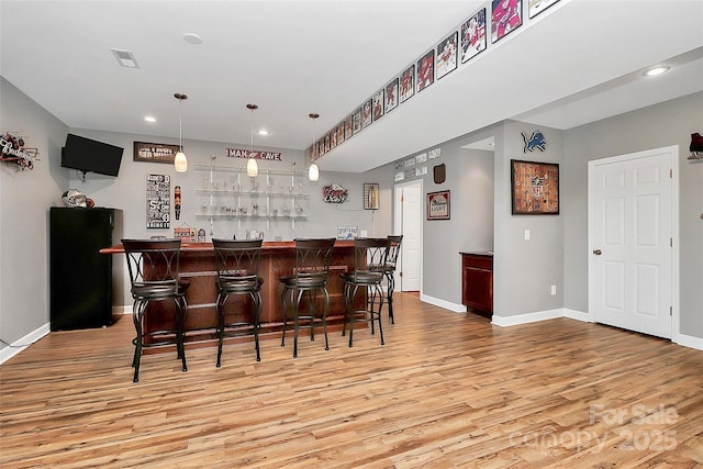 bar with baseboards, visible vents, light wood-type flooring, bar area, and recessed lighting