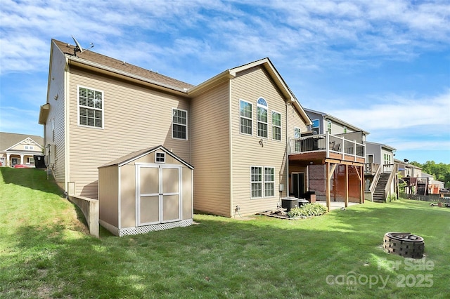 back of house featuring an outbuilding, a lawn, stairway, an outdoor fire pit, and a deck