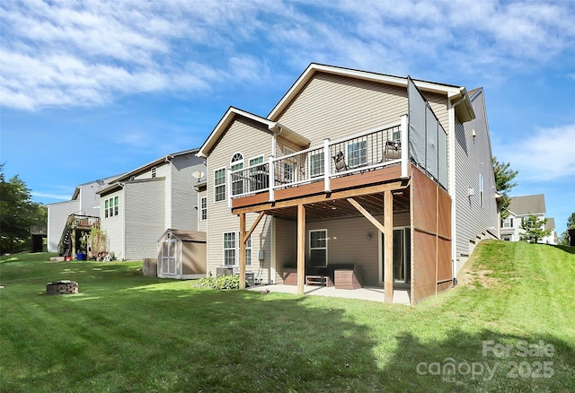 rear view of property featuring a patio, a storage unit, a lawn, an outdoor structure, and a wooden deck