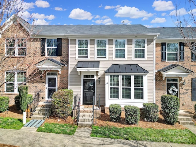 townhome / multi-family property featuring metal roof, brick siding, and a standing seam roof