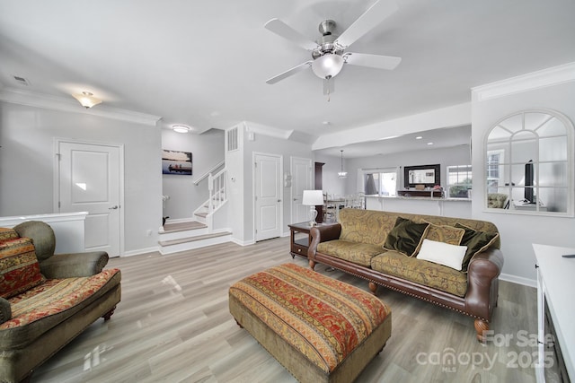 living area with crown molding, stairway, and light wood finished floors