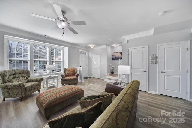 living room featuring crown molding, baseboards, and wood finished floors